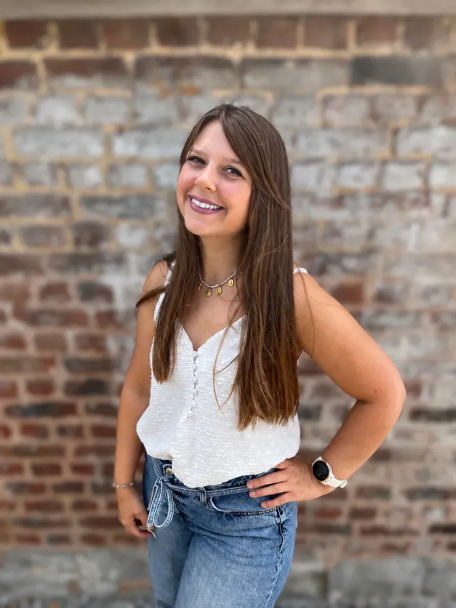 Florie Migeotte, réflexologue, souriante devant un mur de briques