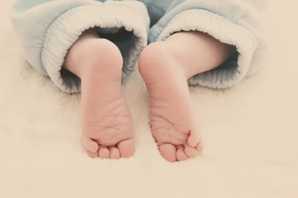 Pieds d'un nourrisson posés sur une couverture claire et douce